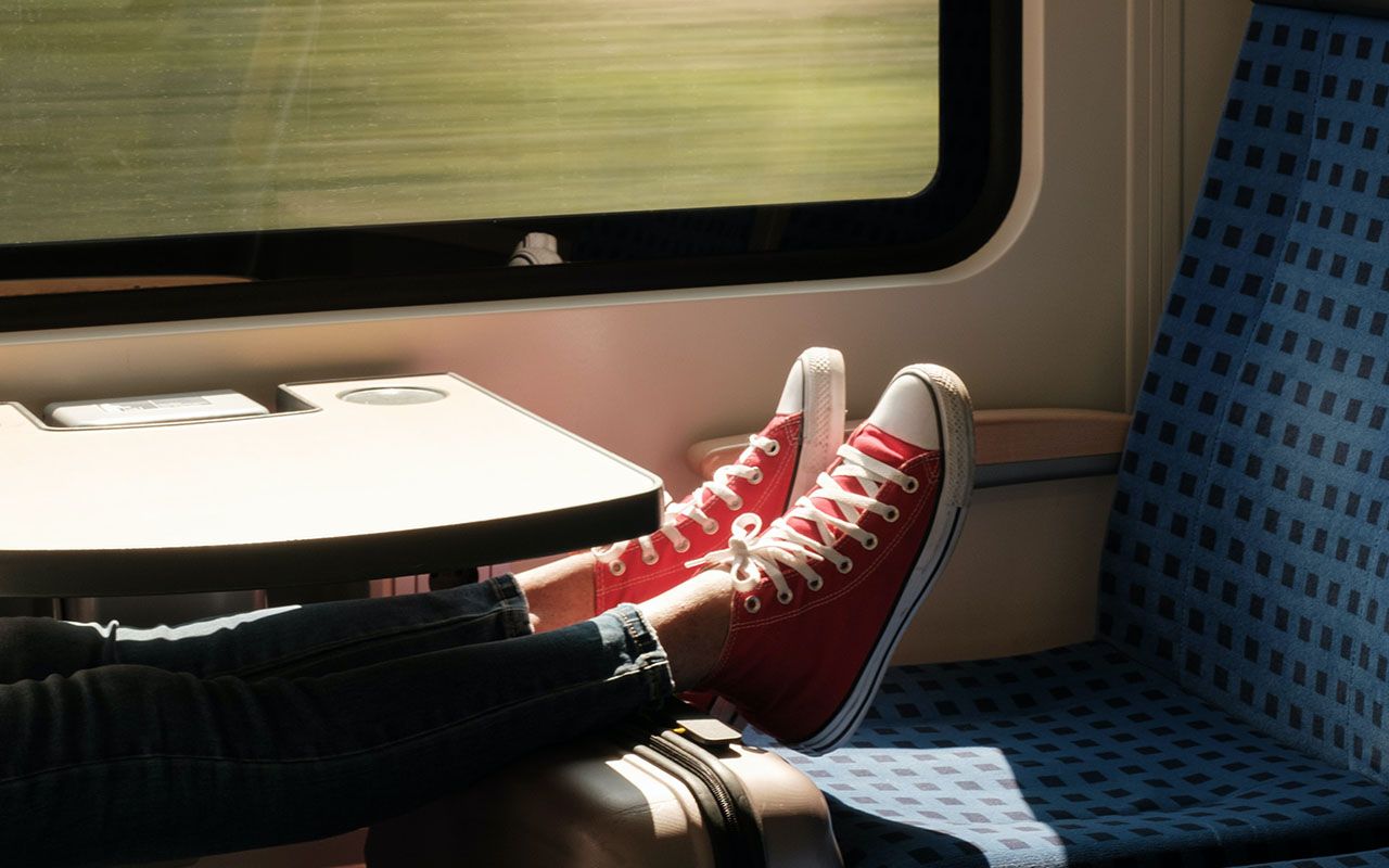 Beine liegen während einer Bahnfahrt sitzend auf einem Koffer hochgelegt
